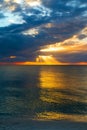Amazing seascape of colorful sunset view from sandy beach, bright sunbeam rays of warm sun light transect the dark cloudy sky Royalty Free Stock Photo