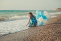 Amazing sensual lady woman with brunette hairs and ice blue eyes with white balloons posing sit for camera on summer sandy beach w