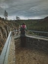 Amazing shot of a female standing in a viewpoint and looking a beautiful landscape