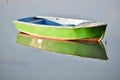 Amazing shot of a green fishing boat on a calm reflective lake background