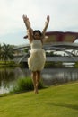 Amazing shot of a happy woman jumping in the park her hands up