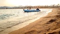 Amazing silhouette photo of inflatable boat with motor rocking on calm ocean waves at the sandy shore against sunset sky Royalty Free Stock Photo