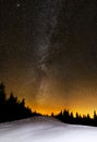 Amazing star night over snowy hill and fir trees