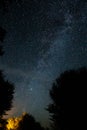 Amazing starry night sky with Milky way and stars above tourists tents in woods in mountains. Camping under the beautiful stars Royalty Free Stock Photo