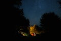 Amazing starry night sky with Milky way and stars above tourists tents in woods in mountains. Camping under the beautiful stars Royalty Free Stock Photo