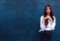 Amazing, stunning red-haired fashionable model on fashion week in white modern blouse on dark blue background. Perfect shot, pictu