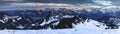 Amazing sunset alpenglow panorama view to snow covered mountain ranges and dramatic sky in cold winter. View from