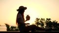 Amazing Sunset Hipster Girl Silhouette Working on Laptop and Drinking Young Thai Coconut. Remote Work in Travel on