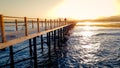 Amazing sunset over the long wooden pier in calm ocean. Sea waves rolling on breaking on the wooden bridge Royalty Free Stock Photo