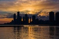 Amazing sunset over sityscape. Cloudy sky with sun rays, water reflection. City modern buildings Royalty Free Stock Photo