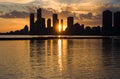 Amazing sunset over sityscape. Cloudy sky with sun rays, water reflection. City modern buildings Royalty Free Stock Photo