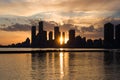 Amazing sunset over sityscape. Cloudy sky with sun rays, water reflection. City modern buildings Royalty Free Stock Photo