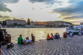 Amazing sunset in Prague anpeople sitting near River Vltava and a little drinking