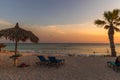 Amazing sunset on sandy beach and Atlantic Ocean. Sun beds and umbrellas on turquoise water and blue orange sky background. Royalty Free Stock Photo