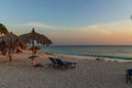 Amazing sunset on sandy beach and Atlantic Ocean. Sun beds and umbrellas on turquoise water and blue orange sky background. Royalty Free Stock Photo