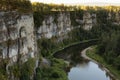 Amazing tranquil mountain canyon landscape with rocky cliffs and precipice with river below and lush green forest in bright golden