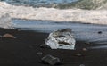 Amazing transparent blue iceberg pieces on Diamond beach with black sand near Jokulsarlon lagoon, Iceland. Ice calving. Black and