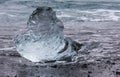 Amazing transparent blue iceberg pieces on Diamond beach with black sand near Jokulsarlon lagoon, Iceland. Ice calving. Black and