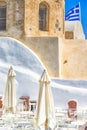 Amazing Travel Destinations. Open Air Caffee  in Oia Village on Santorini Island in Greece.  Old Pale Church on Background Royalty Free Stock Photo
