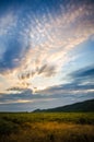 Vertical sunset landscape with the sun hidden behind beautiful swirly clouds