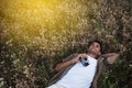Amazing view from above of handsome young man with vintage camera, lying on meadow background. Travel mood. Relaxation on a field. Royalty Free Stock Photo