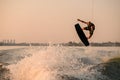 amazing view of active strong male rider holds rope and making jump on wakeboard. Royalty Free Stock Photo