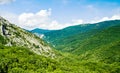 Amazing view of the emerald mountains, hills and ridges covered with green forests. Clear sunny day, blue sky with white clouds. Royalty Free Stock Photo