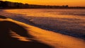 Amazing view of a fiery sunrise with multicolored clouds. Sea waves along the seashore at sunrise