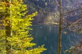 Mountain lake with clear water and a small boat around the autumn forest, the Alps. Royalty Free Stock Photo