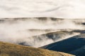 Amazing view of mountain range layers with sea of fog and cloud above the golden yellow dried glass hill in autumn south Patagonia Royalty Free Stock Photo