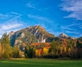 Amazing view on Neuschwanstein Castle with picturesque sky and colorful trees at autumn sunny day, Bavaria, Germany. Royalty Free Stock Photo