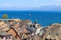 Amazing view over the roofs of old Nyon town at blue Geneva lake or Lac Leman with sailboats and ship and mountains with snow tops