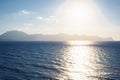 Amazing view of seashore coastline sea waves, mountains surrounded by clouds, sunlight reflecting on water on sunny day.