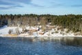 Amazing view of snowy coast of the Baltic sea in winter day. Traditional red wooden houses on the shore.