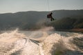 amazing view of the splashing wave and active man jumping in the air with wakeboard Royalty Free Stock Photo