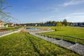 Amazing view of suburbian landscape. Path to little pond and cute compact suburbian houses on blue sky background.