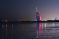 Amazing view to the illuminated Burj al Arab, luxury and modern hotel in Dubai. Colorful lights reflects over the water. Royalty Free Stock Photo