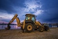 Ellow excavator with a shovel at a construction site in a beautiful twilight Royalty Free Stock Photo