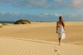 Amazing view of young woman walking barefoot on desert dunes at sunset in Corralejo, Fuerteventura Royalty Free Stock Photo