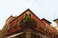 Amazing vintage balcony with many different potted flowers on the corner of medieval red-colored building against blue sky. Royalty Free Stock Photo