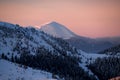 Amazing winter mountain landscape with snow-capped hills and conifers and bright evening sky