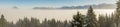 Amazing winter panoramic view to snowy Mountain Range above inversion fog clouds with forest trees. Early morning