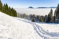 Amazing winter view to snowy Mountains above inversion fog clouds with forest trees. Early morning sunrise view from
