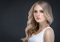 Amazing woman portrait. Beautiful girl with long wavy hair. Blonde model with hairstyle over black background Royalty Free Stock Photo
