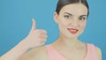 Amazing Woman is Showing Thumbs up on Blue Background in Studio. Beautiful Brunette Gesticulates Looking at the Camera.