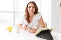 Amazing young lady sitting at the kitchen using tablet computer. Royalty Free Stock Photo