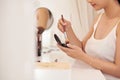 Amazing young woman doing her makeup in front of mirror. Portrait of beautiful girl near cosmetic table Royalty Free Stock Photo