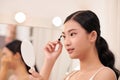 Amazing young woman doing her makeup in front of mirror. Portrait of beautiful girl near cosmetic table Royalty Free Stock Photo