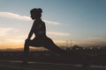 Amazing young woman in sporstwear stretching on road on sunset background. Silhouette of attractive figure, active