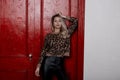 Amazing young woman in stylish black leather pants in a vintage leopard sweater with curly long blond hair is standing Royalty Free Stock Photo